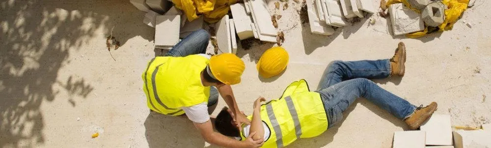 A man lays on the ground after a workplace injury as his co-workers rush to his aide.