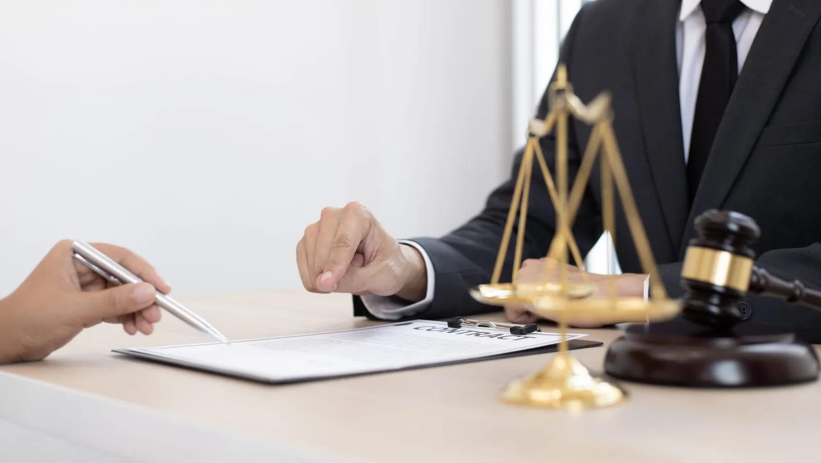 scales and papers on desk and best personal injury attorney pointing at papers