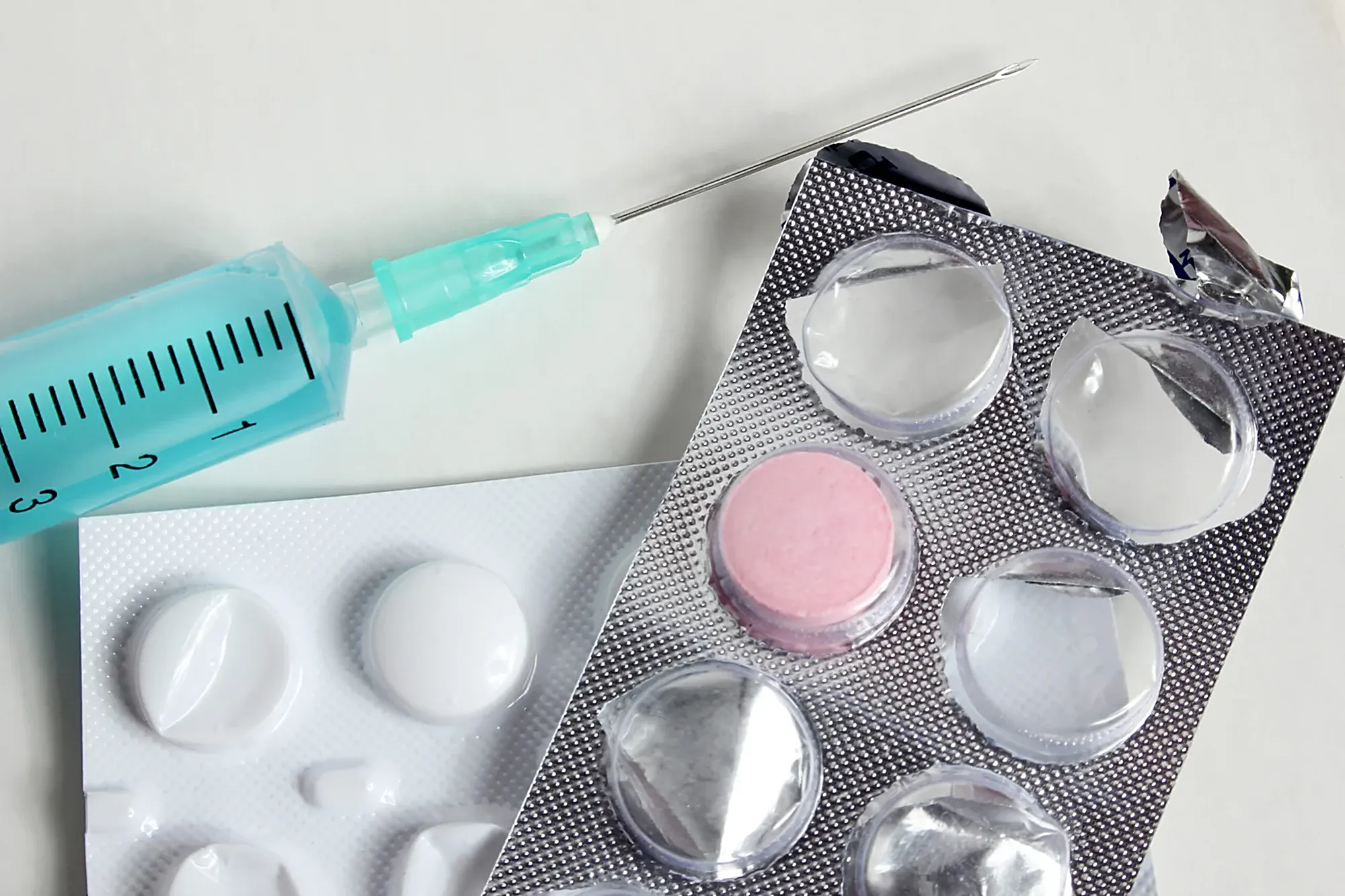 Syringe and medication blister packs on a clinical table