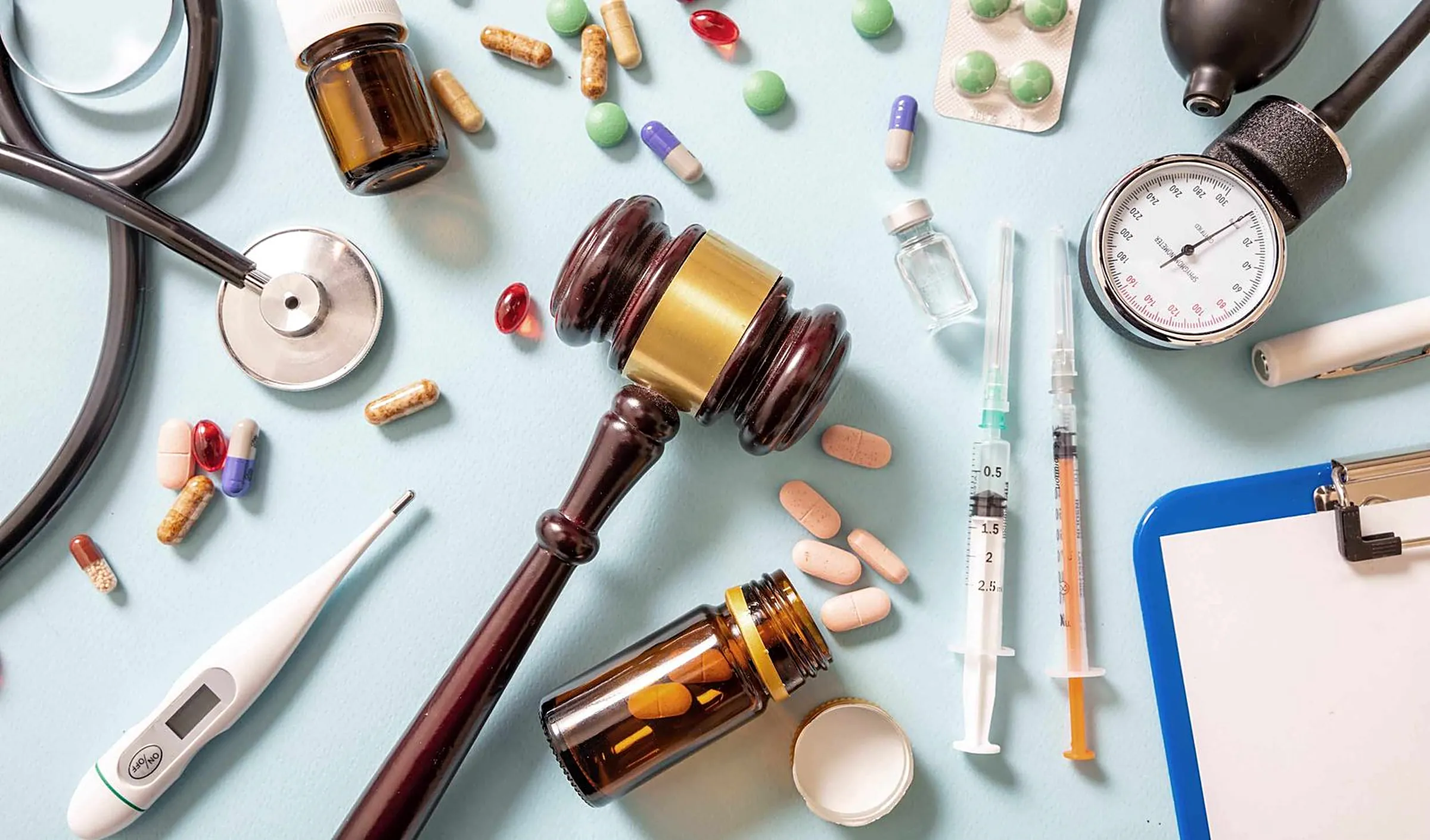 Gavel surrounded by medical equipment and medication