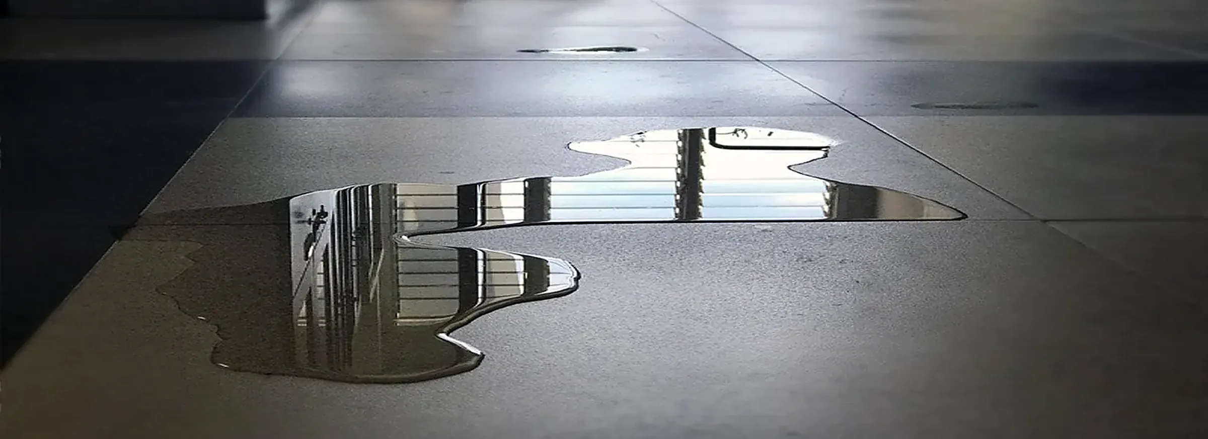 Water puddle creating a slip hazard on a tile floor