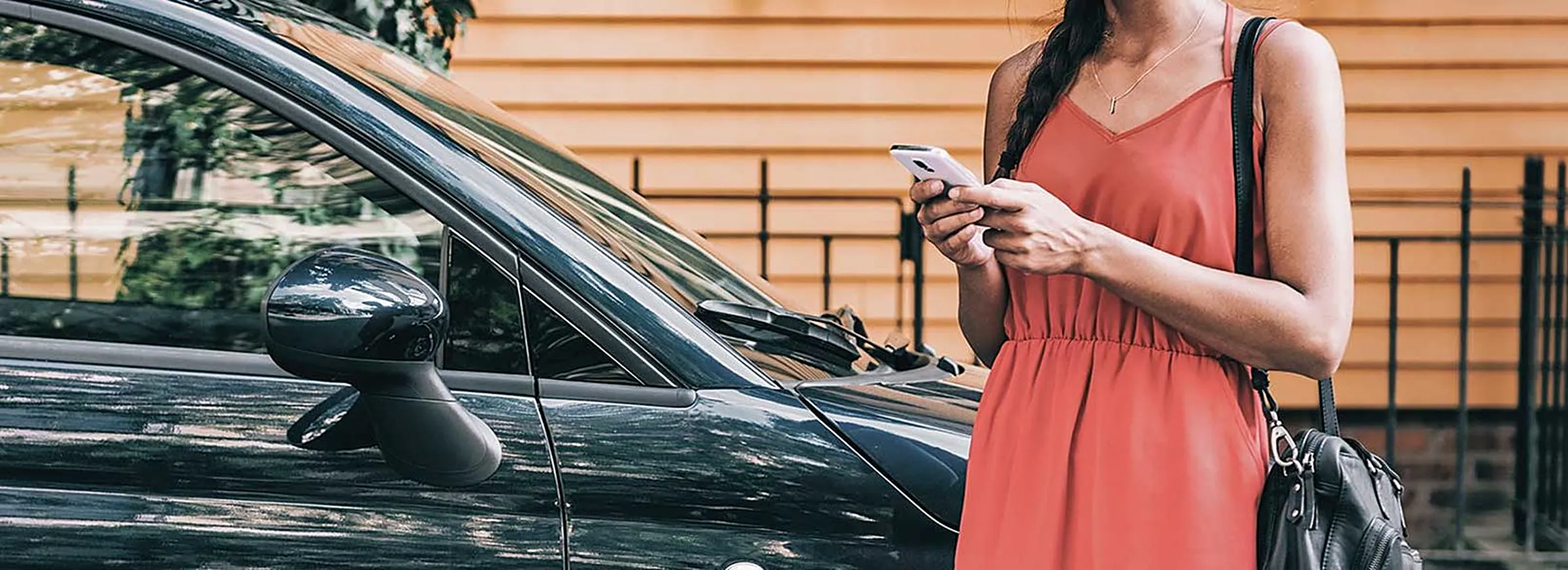 Rideshare passenger checking her phone next to a car
