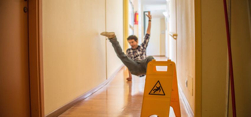 A man falling due to hazardous conditions in a hallway.