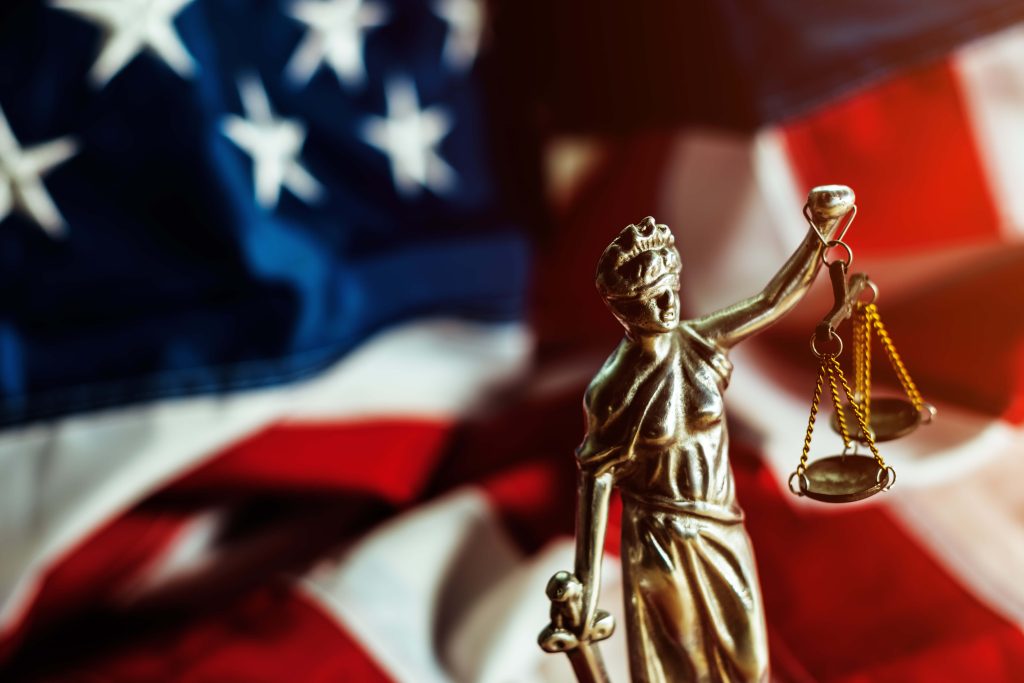 statuette of lady law and american flag in background representing the law and choosing the best personal injury attorney