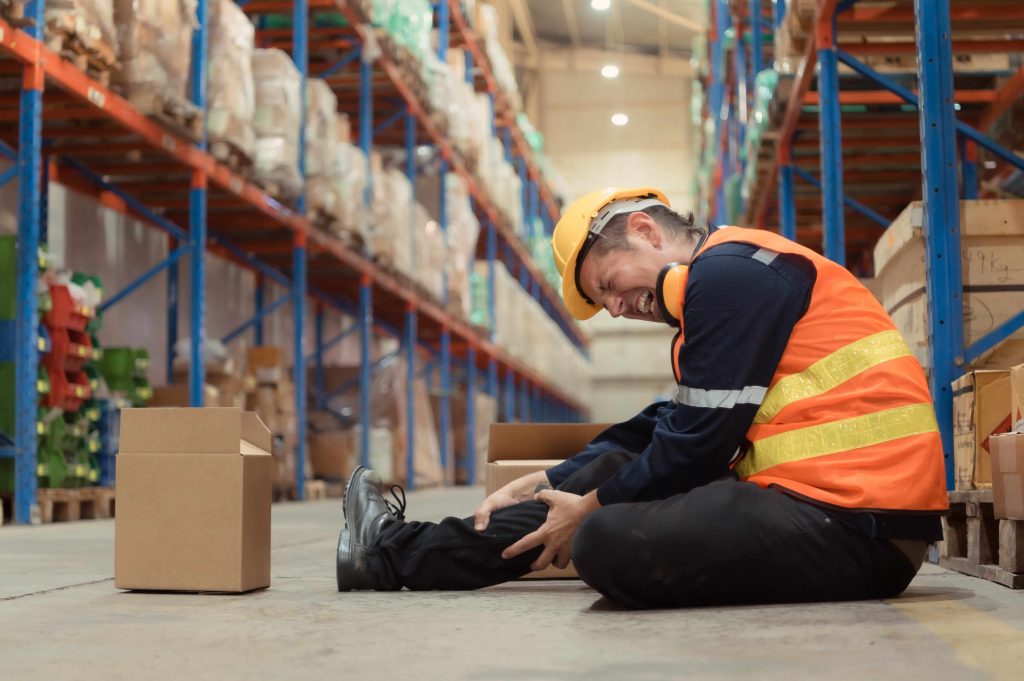 a-warehouse-employee-was-injured-in-an-accident-holding his knee needs workplace injury attorney