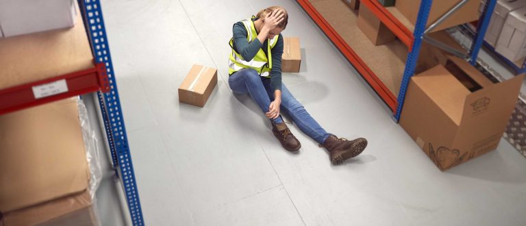 female-worker-with-injured-leg-on-floor-needs workplace injury attorney